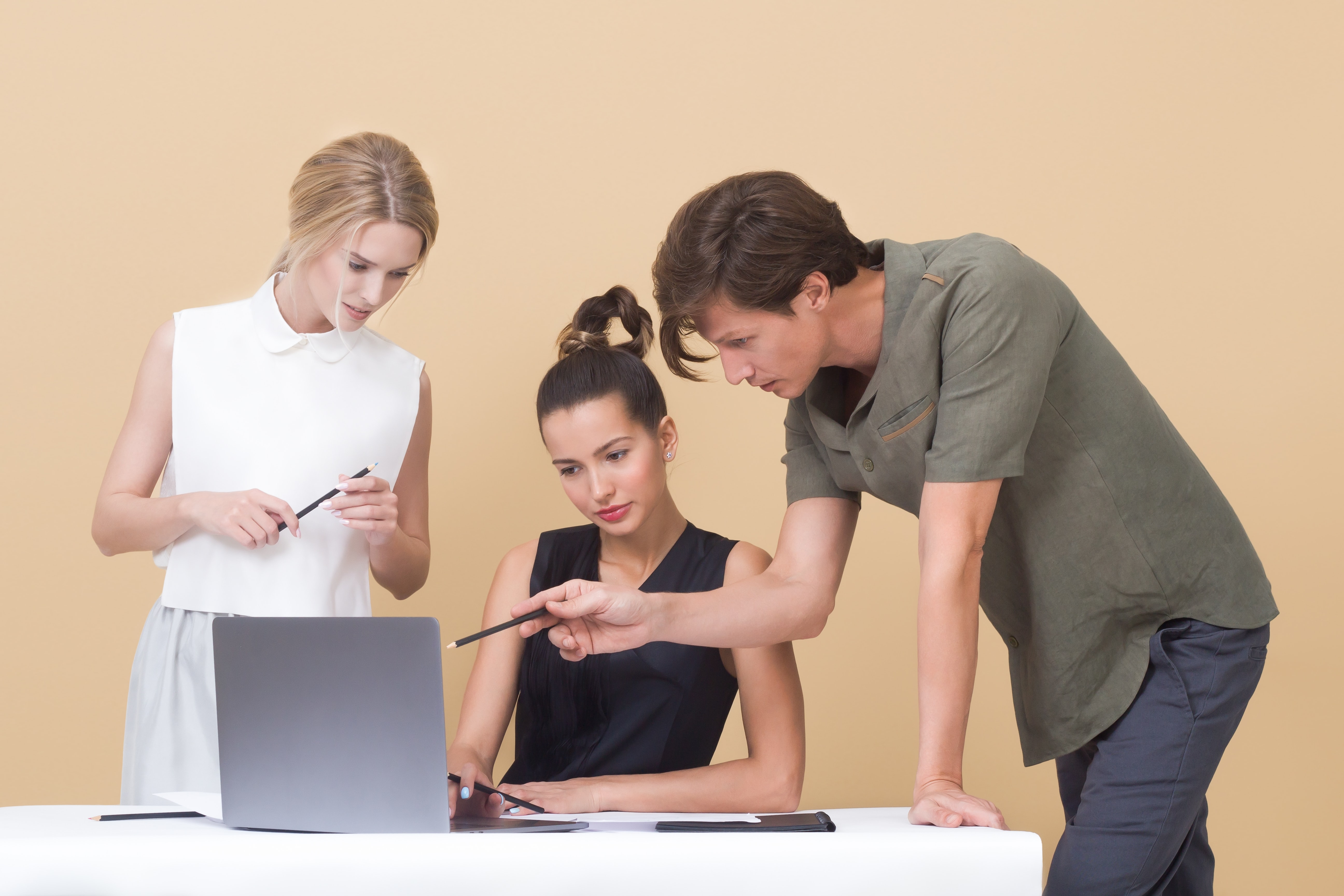 3 people standing. in front of a computer pointing at the screen